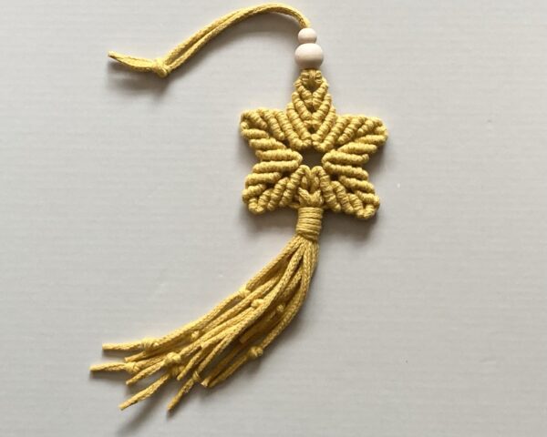 A handmade macrame star in mustard yellow cotton braided cord.