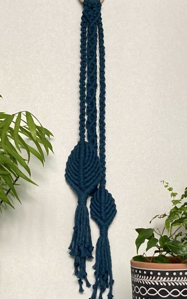 handmade macramé wall hanging/decoration made from a chunky yarn in vibrant teal blue.