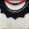 A black macramé wall hanging on a 30cm dowel with red and black bead detail